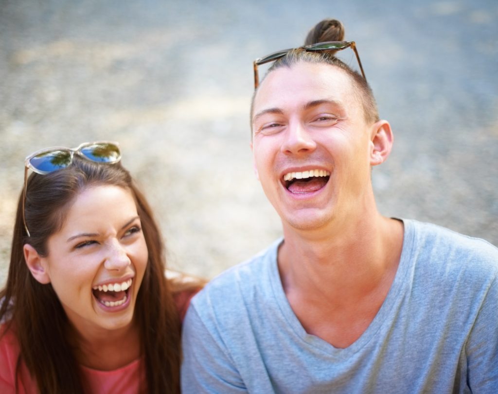 Young at heart. Two young people smiling happily as they sit outside.